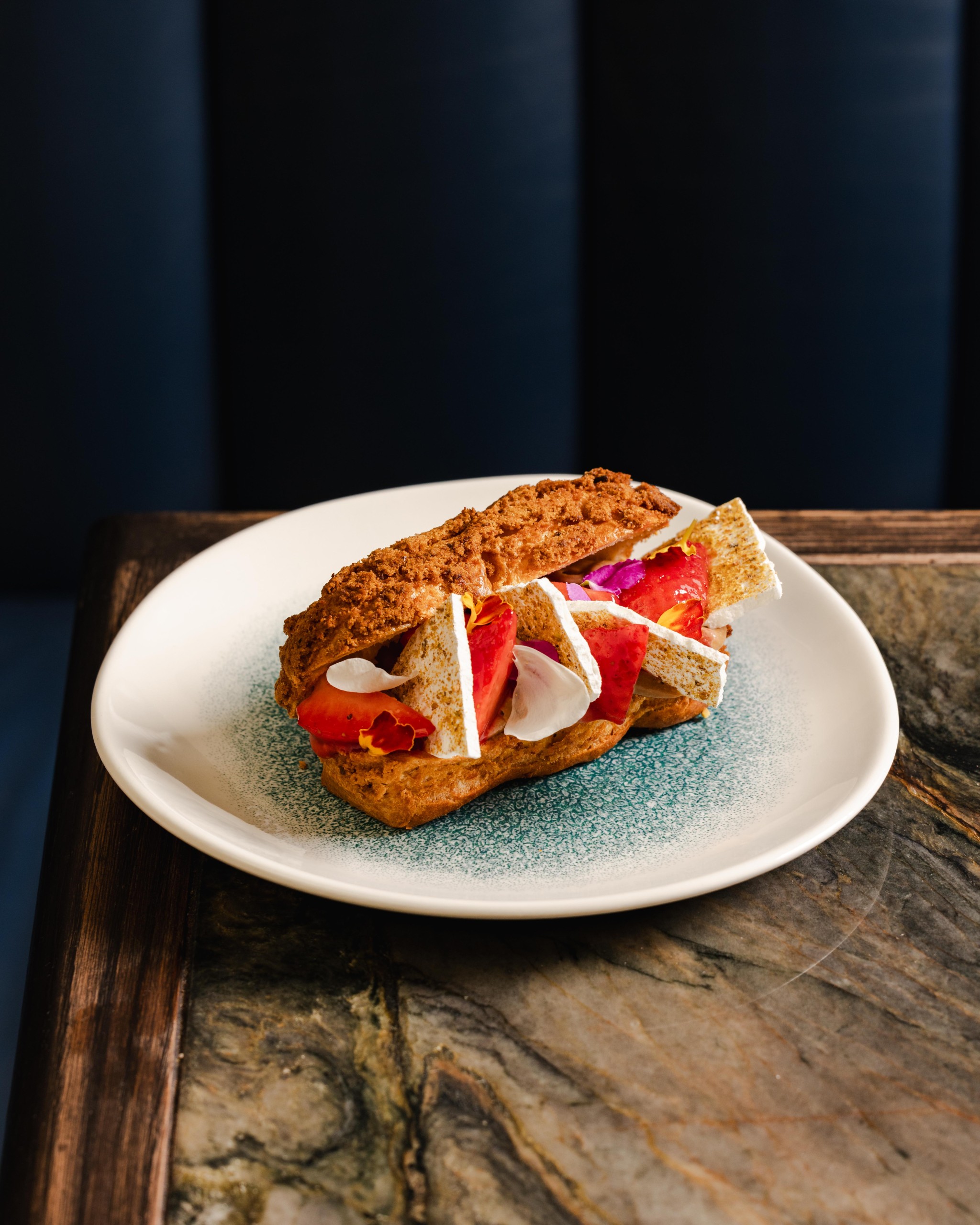 An éclair sliced open with meringue and fresh summer fruits inside