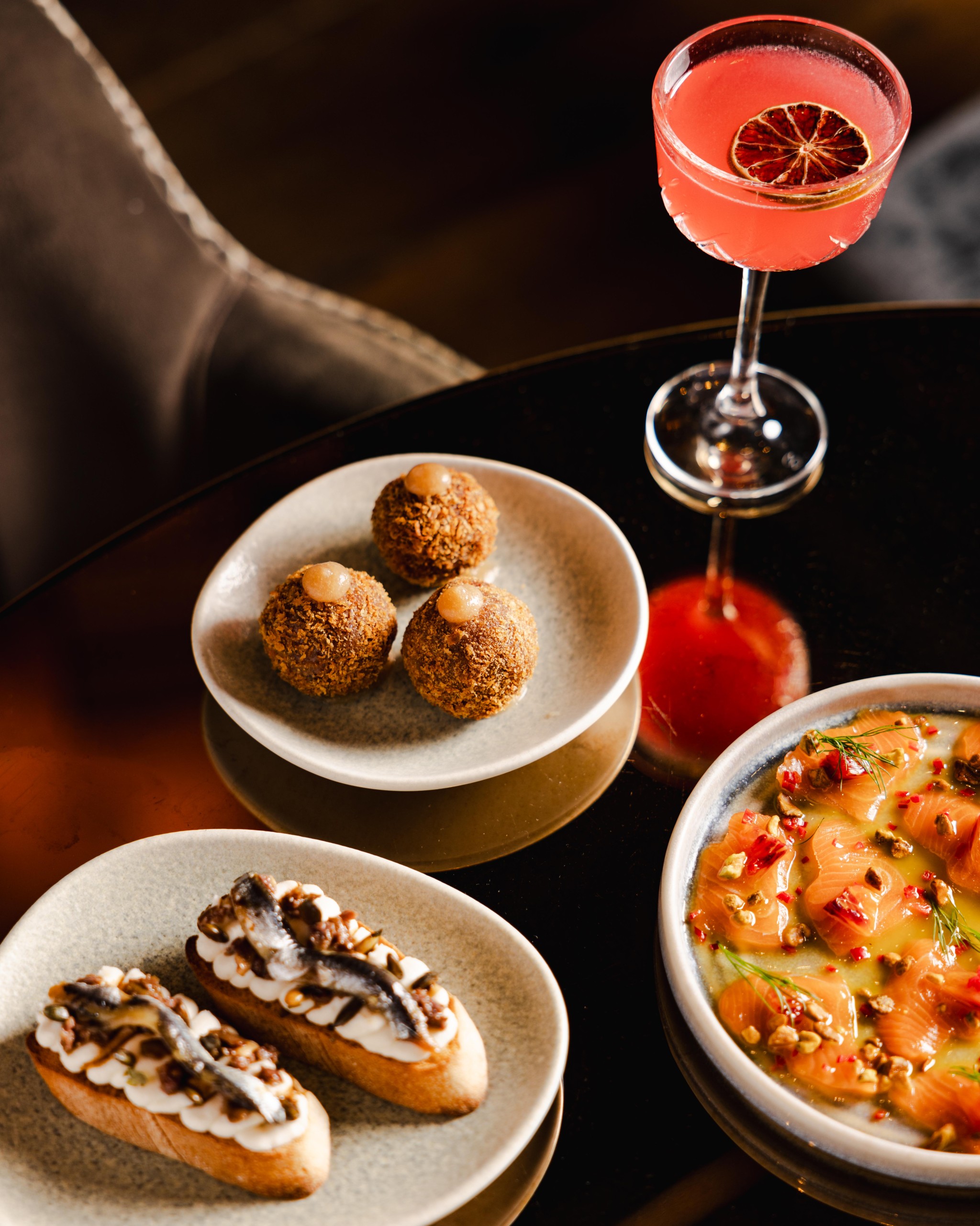 A table of food with a pink cocktail in Bernie's at Groucho
