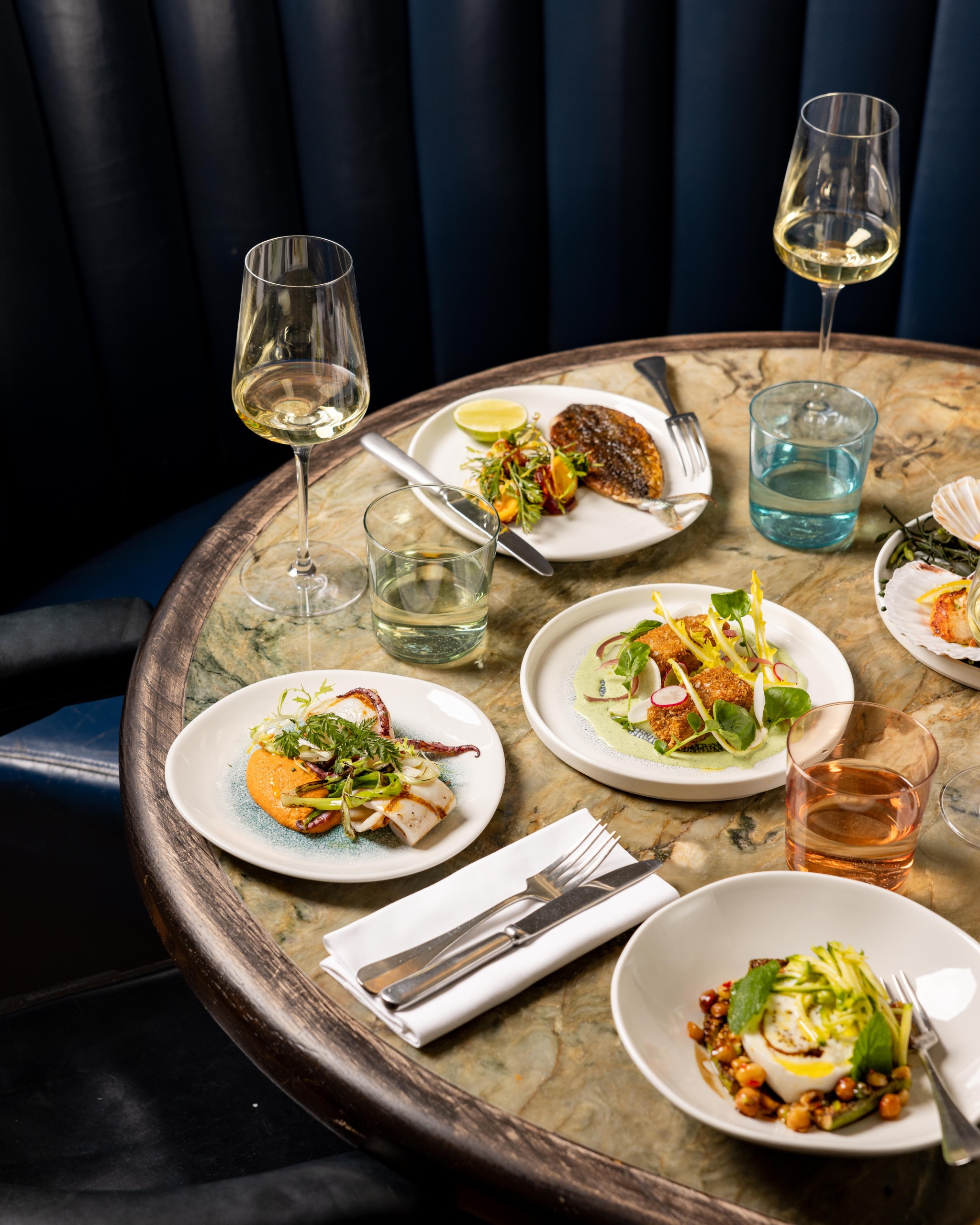 A table of food with two glasses of wine in The Dining Room at Groucho